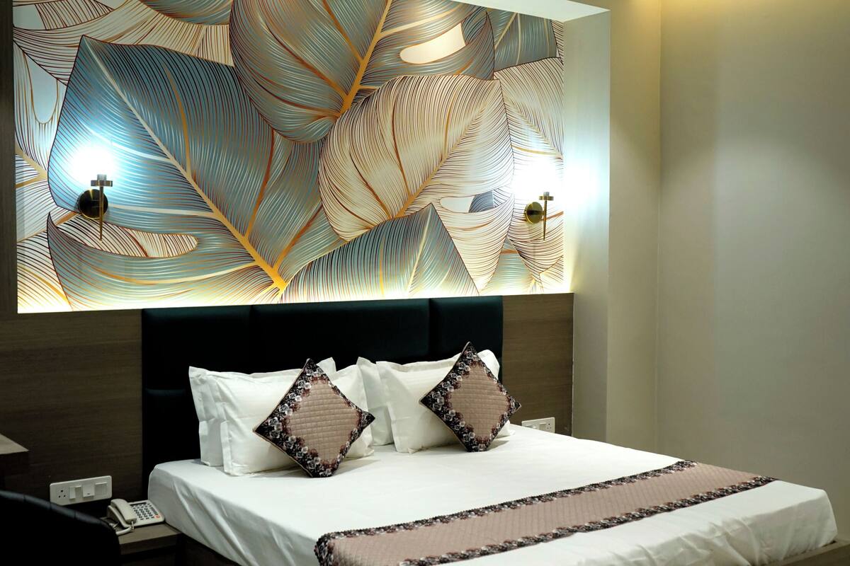 A modern bedroom with a large bed, a ceiling fan, and a wall with a leaf pattern.
