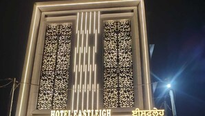 A hotel entrance with a modern facade, illuminated signage, and a visible parking area. - Hotel Eastleigh (Ludhiana)
