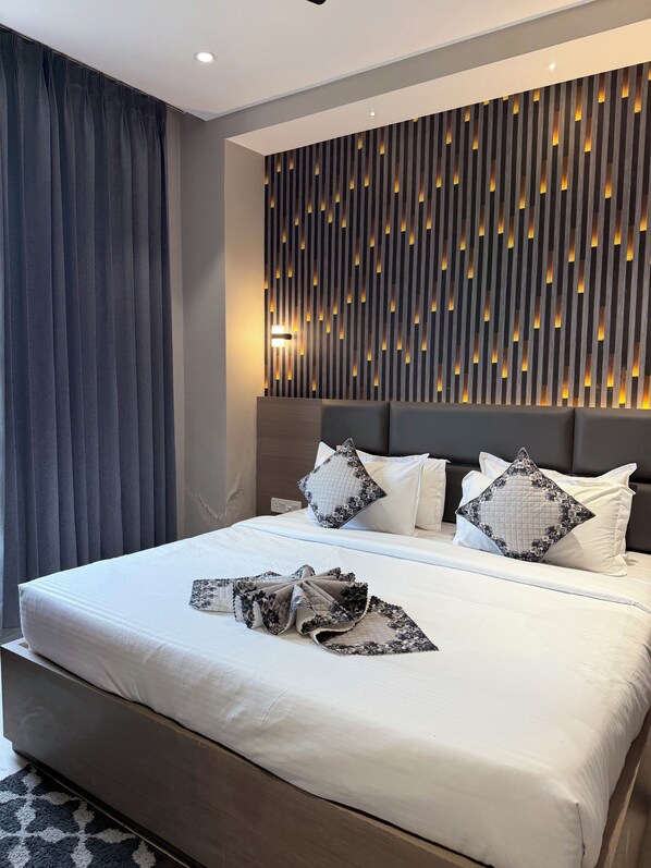 A modern hotel room with a neatly made bed, a headboard with built-in lighting, and a patterned wall.