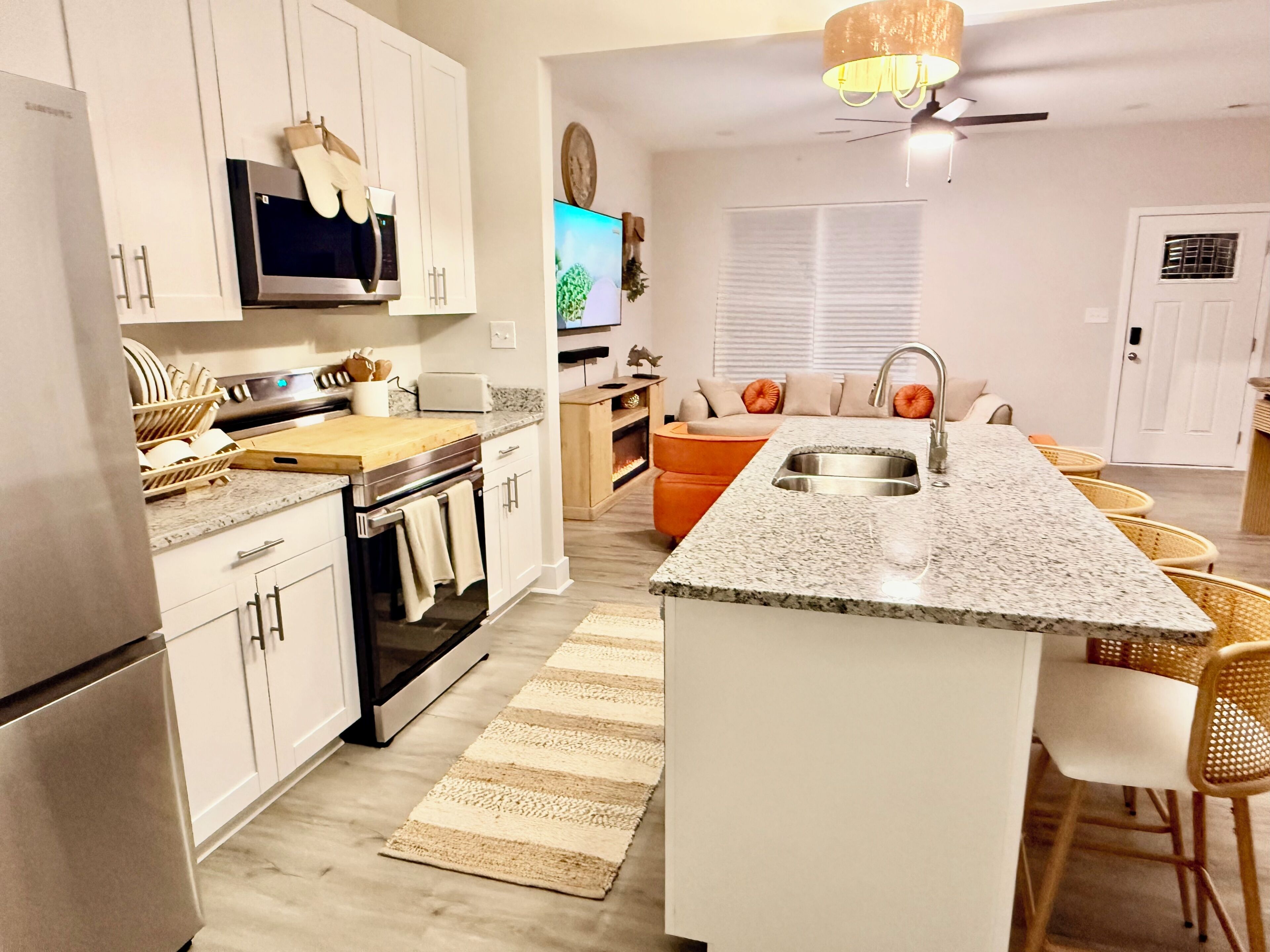 A modern kitchen with white cabinetry, a built-in oven, a microwave, and a granite countertop.
