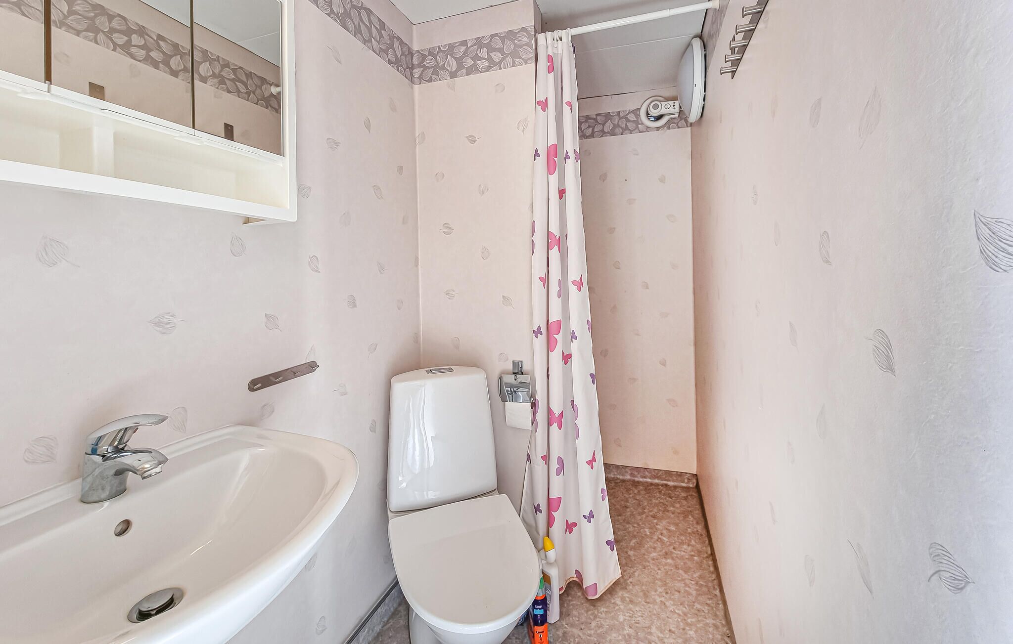 Un bagno con lavandino, WC e tenda per la doccia.