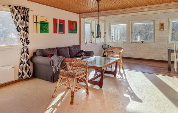 A room with a sofa, wicker chairs, a glass-top table, and artwork on the wall.