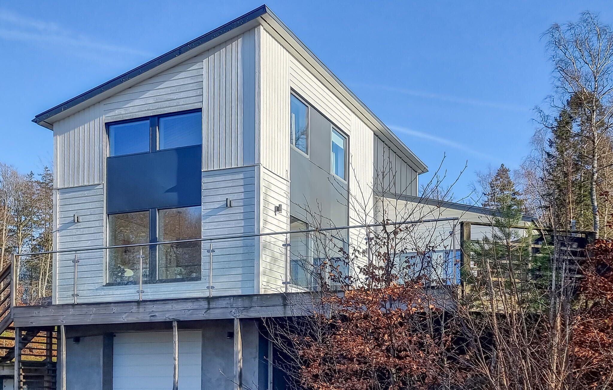 Un bâtiment moderne à deux étages, doté d’un toit plat, de grandes fenêtres et d’un balcon bien visible.