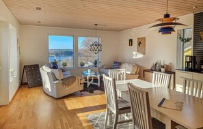A modern living room with a dining area, large windows, and a view of the outdoors. - Awesome home in Uddevalla with house sea view (Uddevalla)
