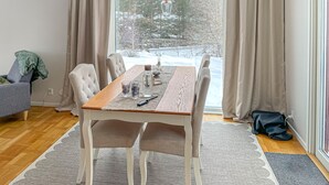 Ein Essbereich mit einem Holztisch, Stühlen und Blick auf eine verschneite Landschaft.