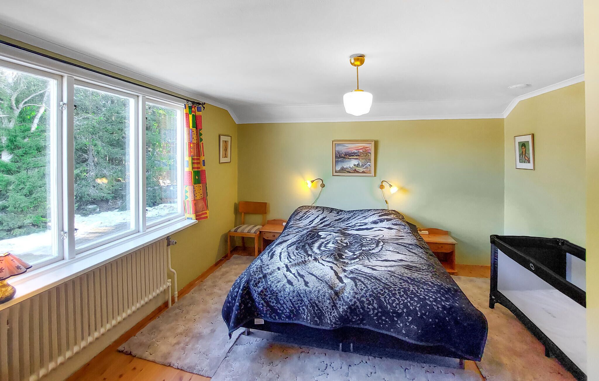 Een slaapkamer met een bed, een raam, een radiator, een bureau en een stoel.