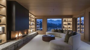 Ein modernes Wohnzimmer mit Kamin, einer großen Couch und Blick auf die Berge.