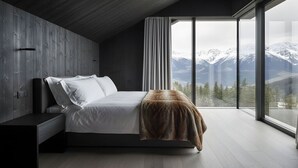 Ein modernes Schlafzimmer mit großem Fenster, einem Bett, einem Nachttisch und Bergblick.