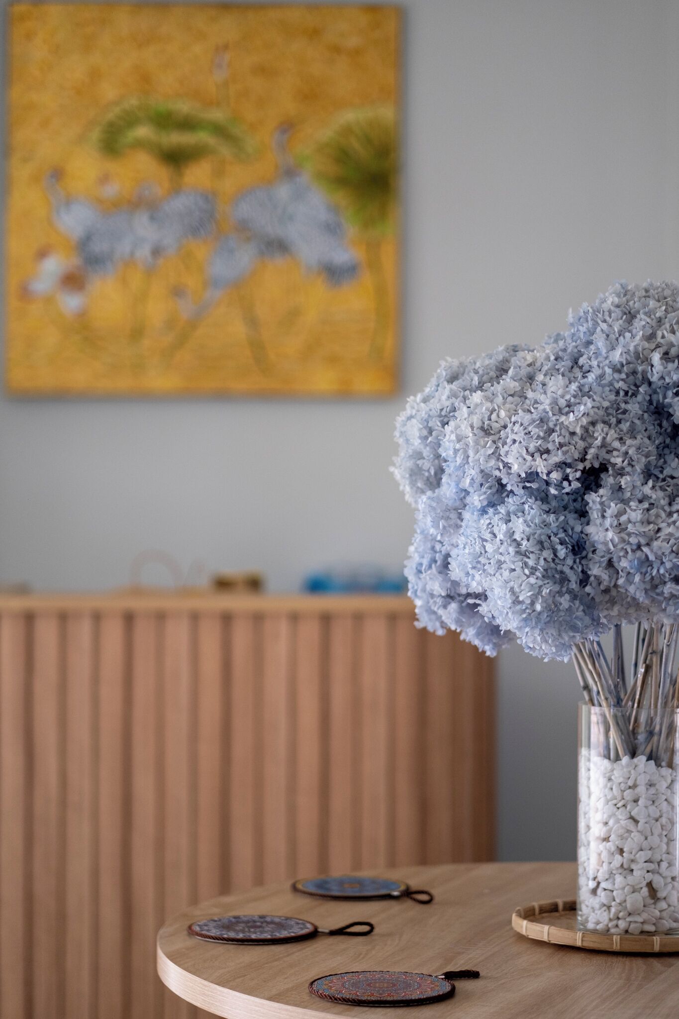 Una mesa de madera con un jarrón de flores y dos posavasos.