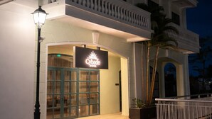 Entrada de hotel con un cartel, un farol y una puerta con reja.