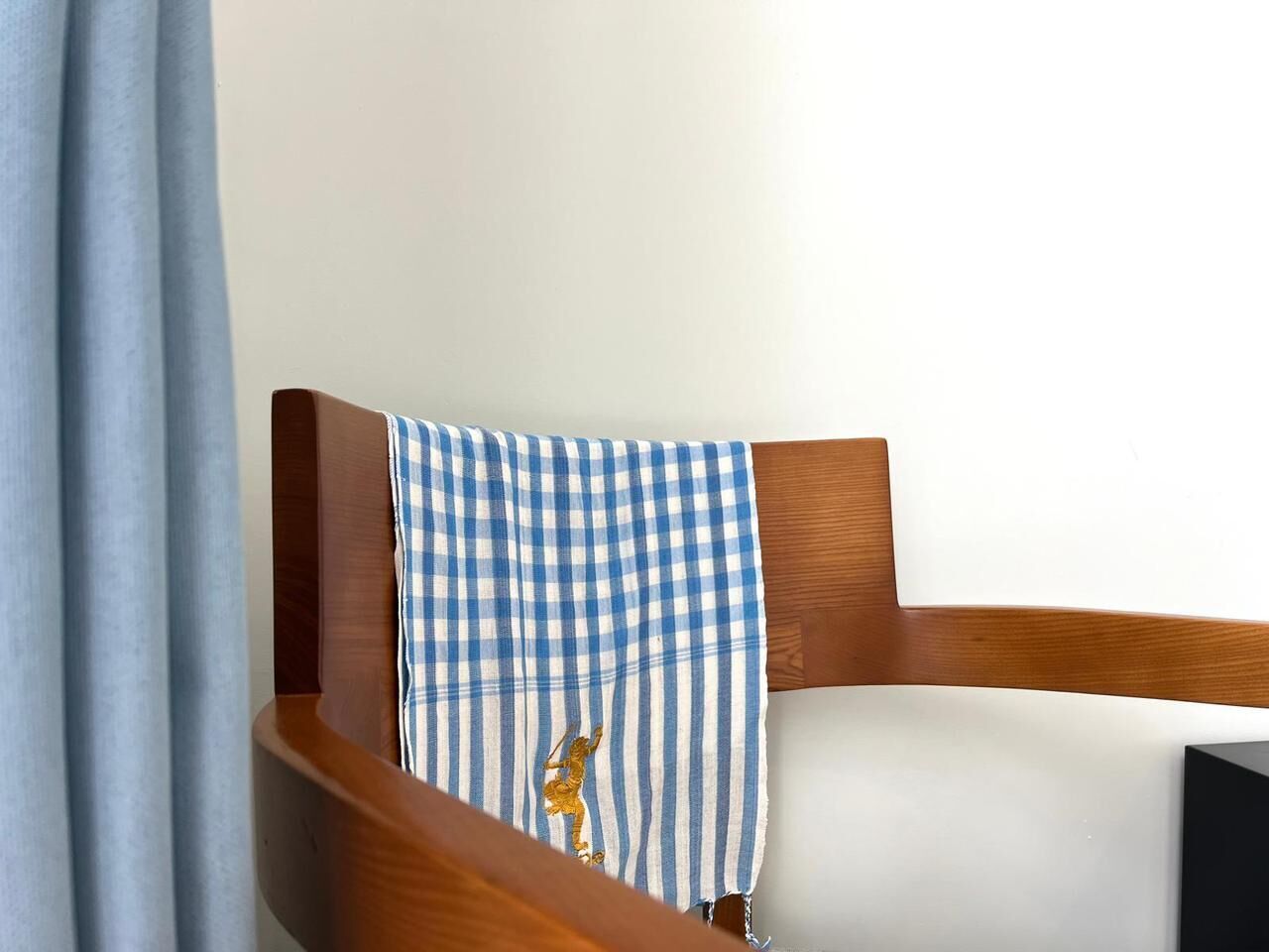 A wooden chair with a checkered cloth draped over it.
