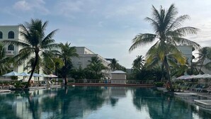 Una piscina con palmeras y un edificio al fondo.