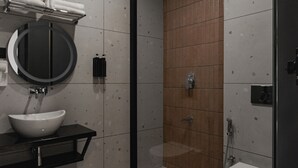 Un baño moderno con un espejo redondo, lavamanos blanco y cabina de ducha.