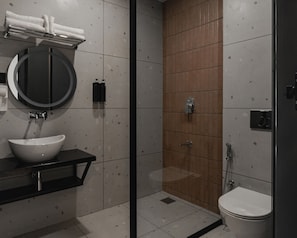 Ein modernes Badezimmer mit rundem Spiegel, weißem Waschbecken und Duschkabine.