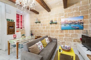 A cozy living room with a stone wall, a sofa, a dining table, and a television.