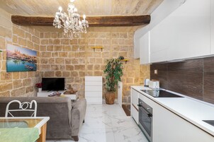 A modern kitchen with white cabinets, a built-in oven, and a stone wall backdrop.