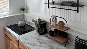 A kitchen with a white countertop, wooden cabinets, a black kettle, a coffee maker, and a toaster. - Fantastic 1-bedroom townhome apartment in Spokane perfect for your getaway (Spokane)