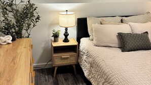 A bedroom with a bed, a bedside table with a lamp, a wall-mounted decorative item, and a potted plant. - Fantastic 1-bedroom townhome apartment in Spokane perfect for your getaway (Spokane)