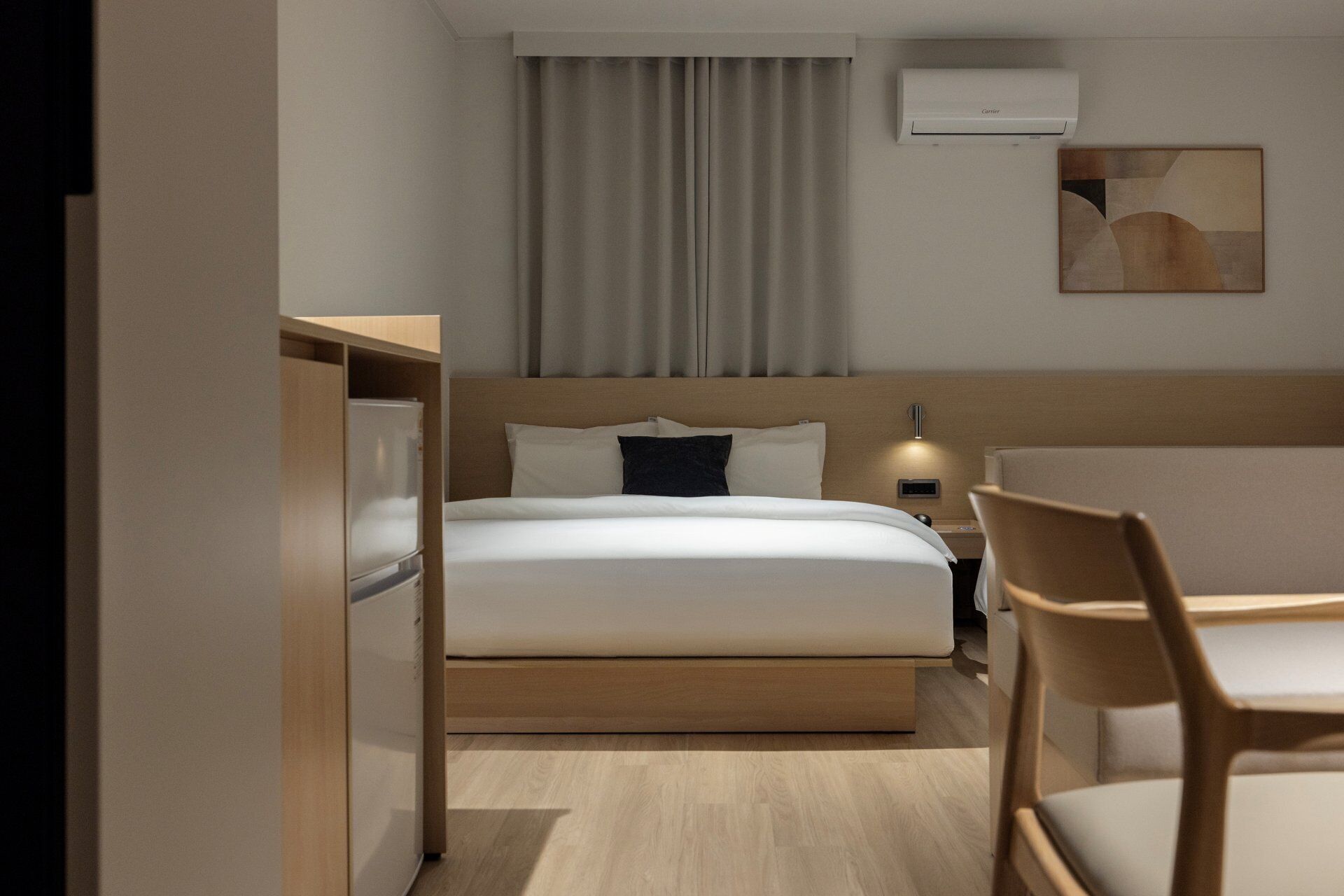 Une chambre d’hôtel équipée d’un lit, d’une table de chevet, d’une chaise et d’un climatiseur fixé au mur.