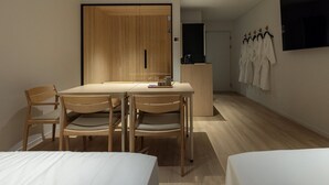 Habitación de hotel con mesa de comedor de madera, cuatro sillas, una cama, un escritorio y un armario.