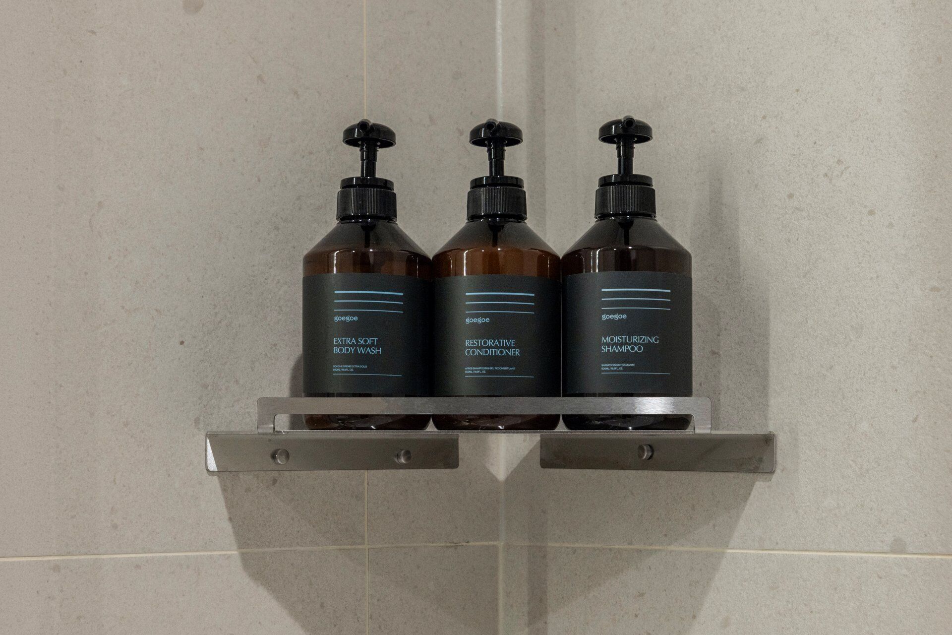 Tres botellas de gel de baño, acondicionador y champú en una estantería.