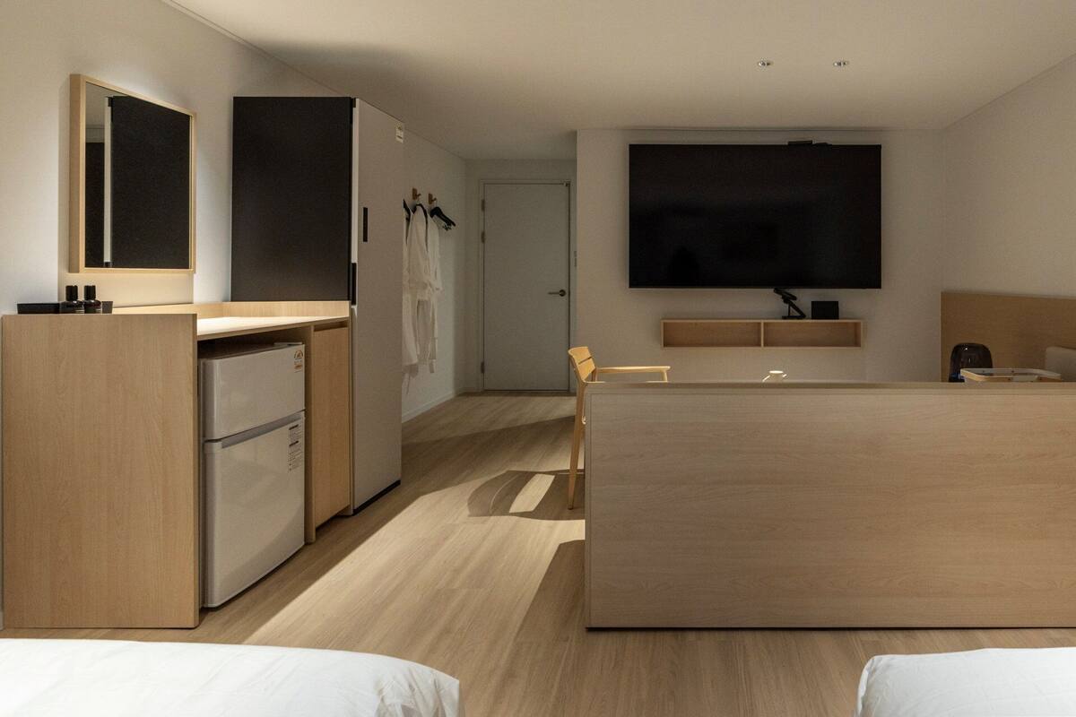 A modern hotel room with a kitchenette, a flat-screen TV, a bed, and a seating area.
