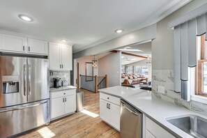 Una cocina moderna con electrodomésticos de acero inoxidable, armarios blancos y piso de madera.