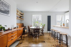 Une cuisine avec un plancher en bois, une table à manger avec des chaises, une bibliothèque intégrée et une fenêtre donnant sur un beau paysage.