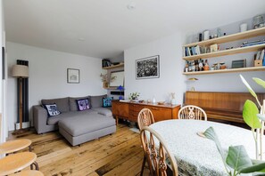Un salon chaleureux avec un canapé gris, une table basse en bois et un coin repas doté d’une table ronde.
