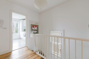 A staircase with a white railing leading to a landing. A framed artwork is visible on the wall. - Serene 1BD by London Fields and Victoria Park (Greater London)
