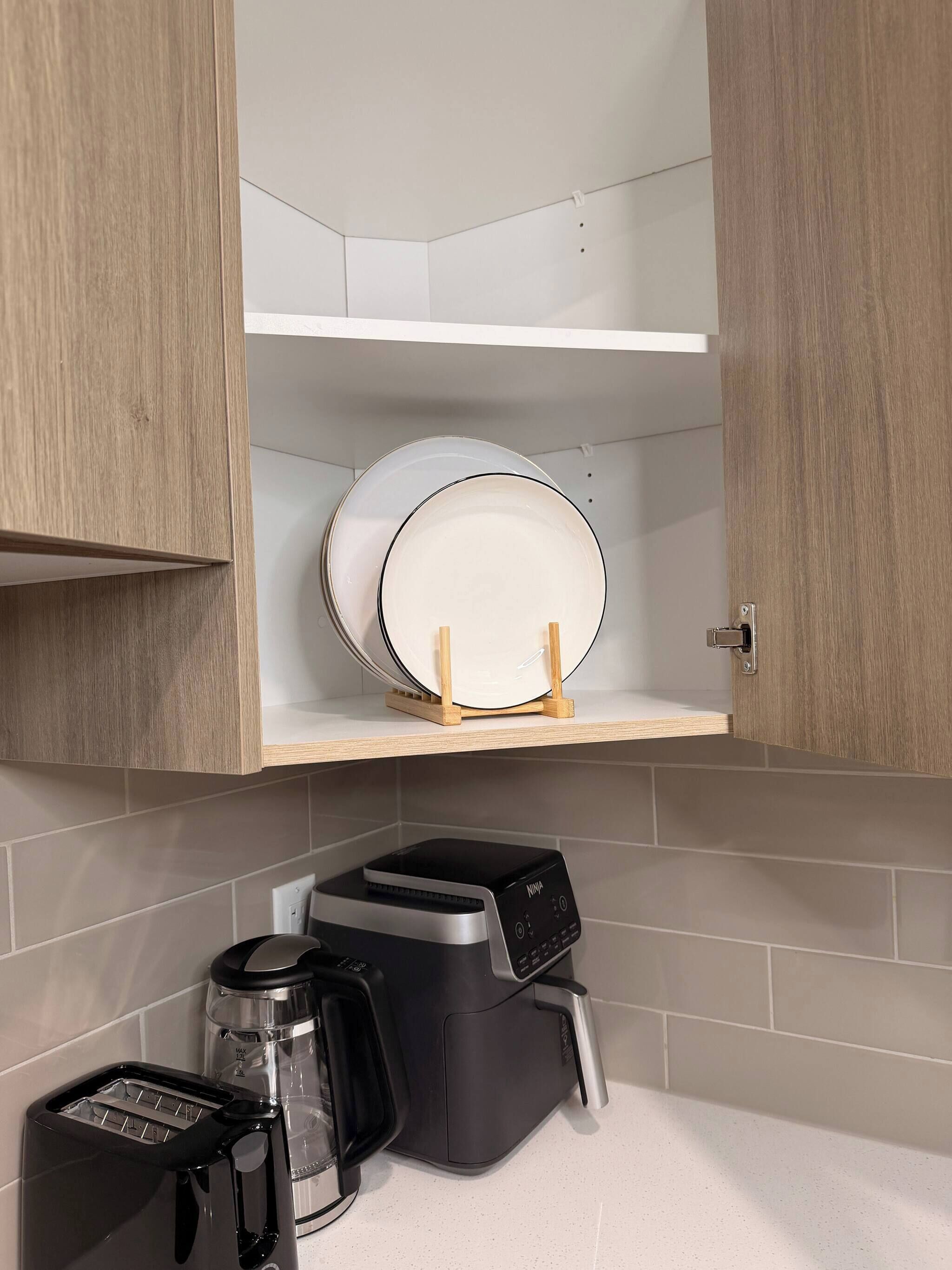 A kitchen with a toaster, coffee maker, and a white plate on a shelf.