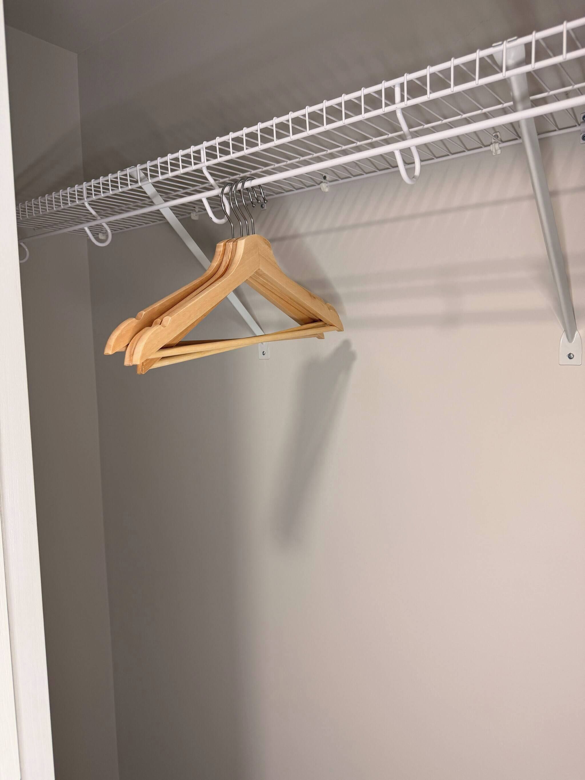 Um varal de metal branco com cabides de madeira.