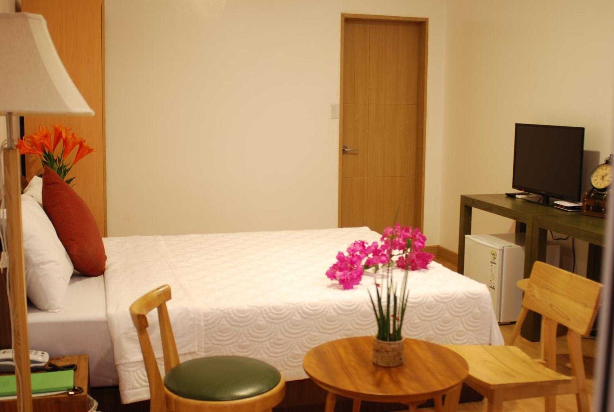 A hotel room with a bed, a desk with a computer, a chair, and a small table.