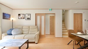 Una sala de estar moderna con un sofá, una mesa de comedor y una escalera que lleva a otra habitación.