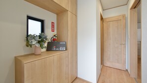 Un pasillo con paredes de madera, una planta en maceta, un extintor y una puerta.