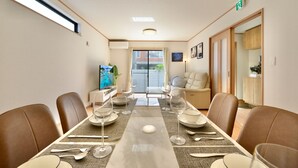 Comedor con una mesa larga dispuesta para seis comensales, rodeada de sillas de cuero, y vista al exterior a través de un ventanal grande.