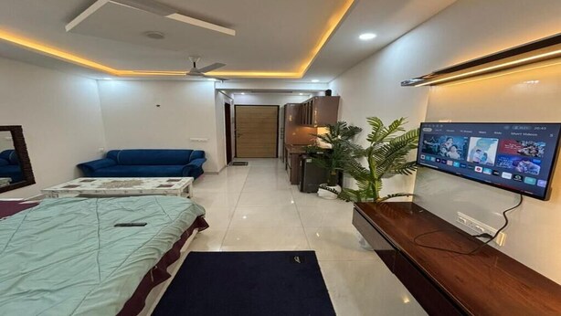 Un dormitorio moderno con cama, sofá, televisor y ventilador de techo.