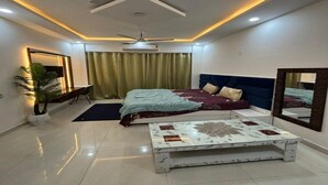 Un dormitorio moderno con cama, mesita de noche, ventilador de techo y un espejo grande.