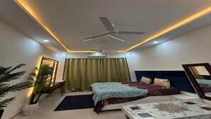 Un dormitorio con cama, ventilador de techo, espejo y planta en maceta.