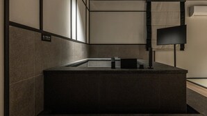 Un baño moderno con un lavamanos rectangular, paredes con azulejos y un letrero de precaución.