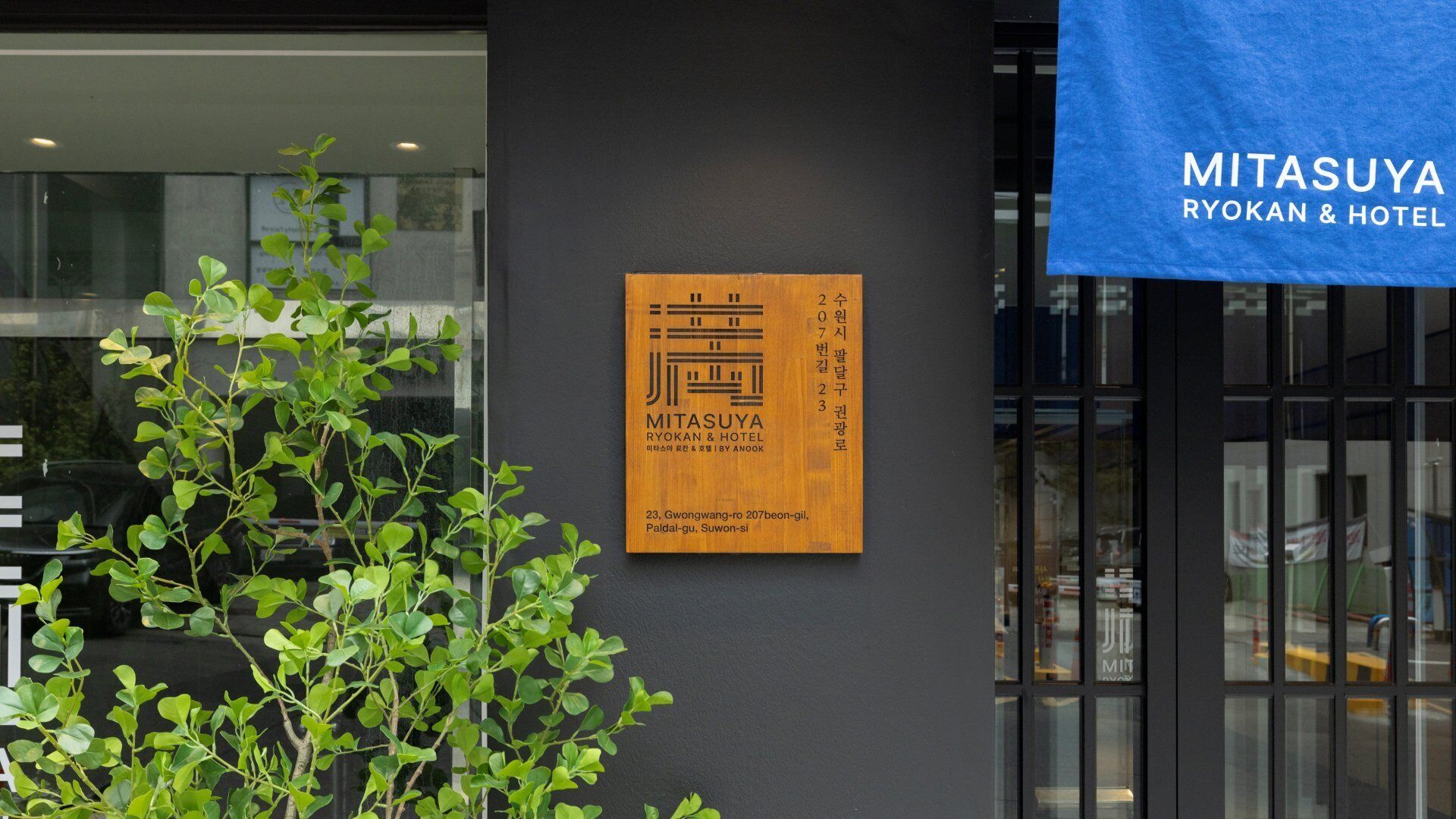 A hotel sign with the name 'MITSASUYA RYOKAN & HOTEL' and a wooden plaque with the address.