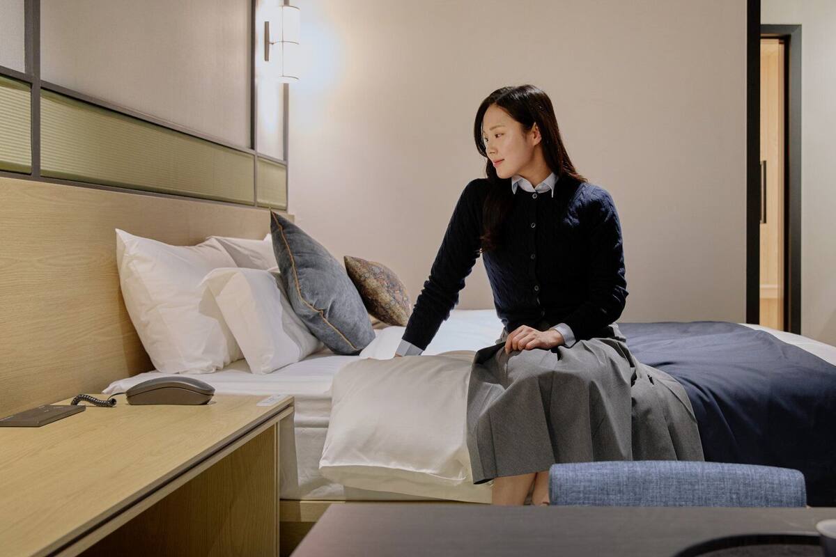 Una habitación de hotel con cama, mesita de noche y escritorio con teléfono.