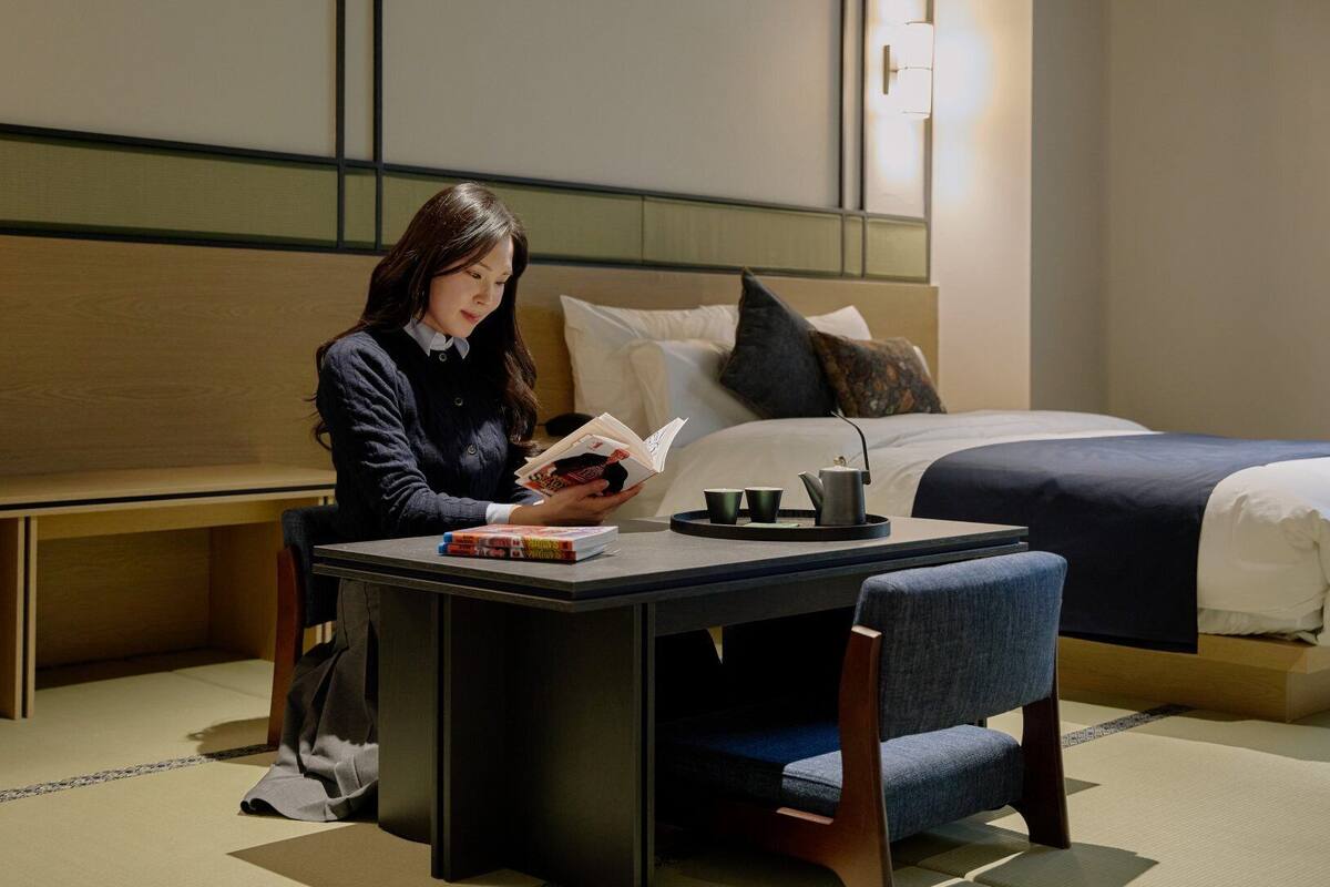 Una habitación de hotel con una cama, una mesa de lectura y una estantería.