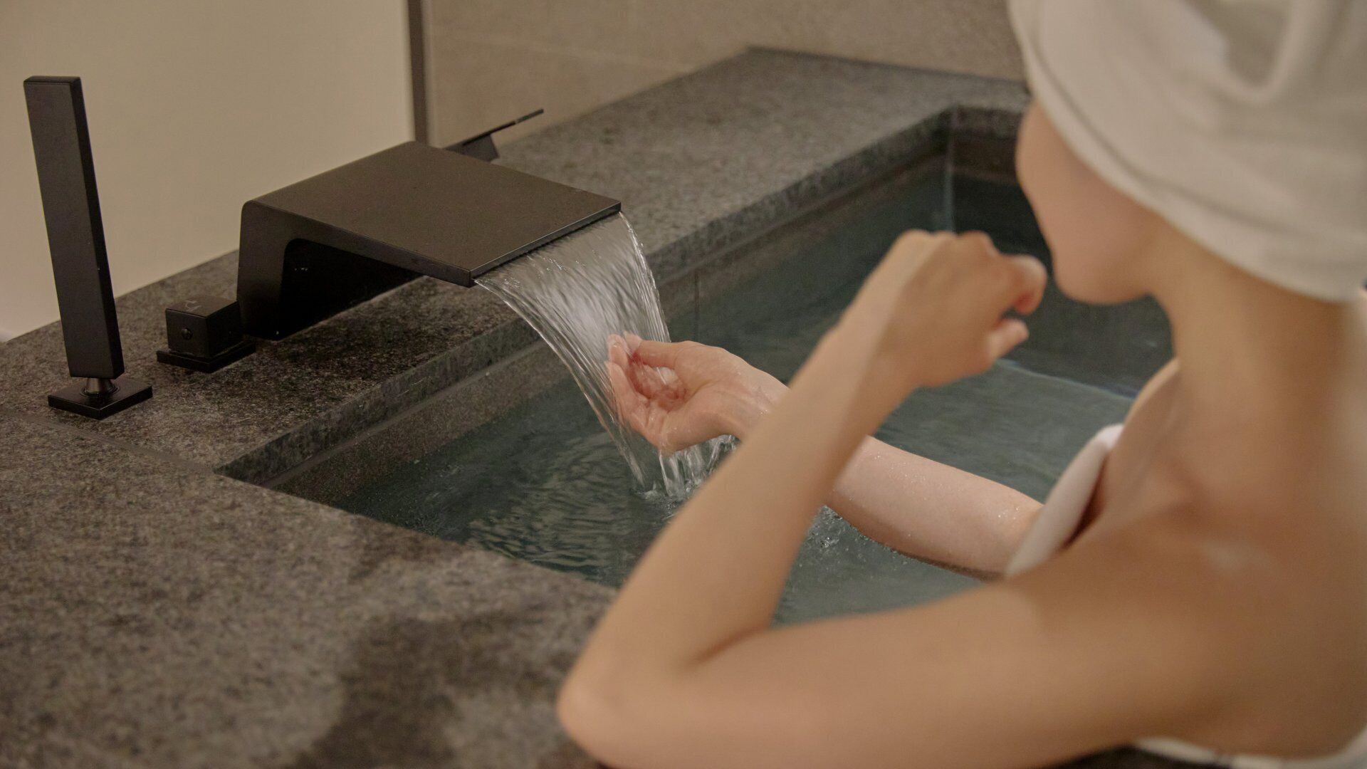 A person in a bathtub with a faucet.