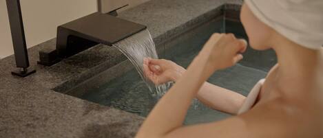 A person in a bathtub with a faucet.