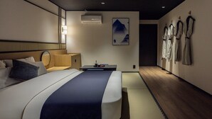 Una habitación de hotel moderna con una cama grande, una mesita de noche y un aire acondicionado de pared.