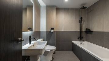 A modern bathroom with a toilet, sink, and bathtub, featuring a minimalist design and neutral color palette.