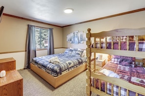 Ein Schlafzimmer mit einem hölzernen Bett, einem Nachttisch aus Holz, einem Fenster mit Vorhängen und einer Wand mit gerahmten Bildern.