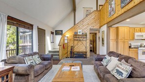 En rummelig opholdsstue med et træsofabord, lædersofaer og en trappe til en etage over.