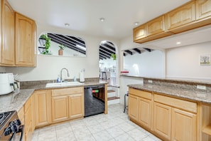 A modern kitchen with wooden cabinets, granite countertops, a dishwasher, and a built-in oven. - Bay Area Family Home w/ Indoor Pool + Game Room (South San Francisco)
